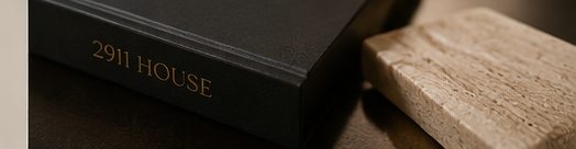 Visualization of a black linen House book stamped in brass beside a slab of travertine.