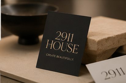 Visualization of a black 2911 HOUSE card with brass lettering resting on travertine.