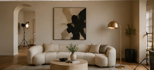 Visualization of the Studio: low sofa, abstract canvas, a brass floor lamp and a production light on a stand.
